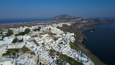 Smooth panning shot over Santorini, Greece. Aerial view over Thira, featuring the white buildings and blue domes. 