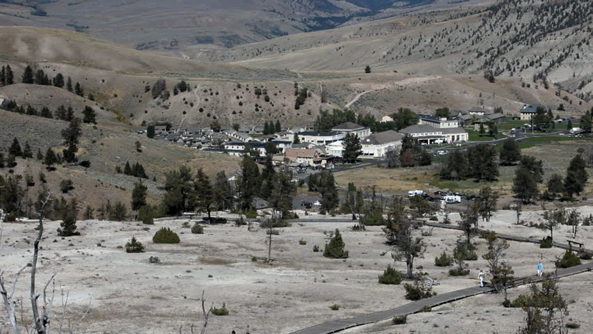 YELLOWSTONE NATIONAL PARK, WYOMING: Mammoth Hot Springs town from the  Cascade boardwalk, Yellowstone National park, Wyoming. Tourists walking and enjoying view. Hot steam geothermal feature.