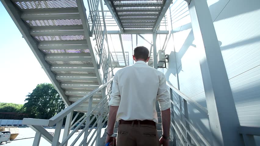 Attractive young man with high security bulletproof protected case climbing modern stairs outside the building
