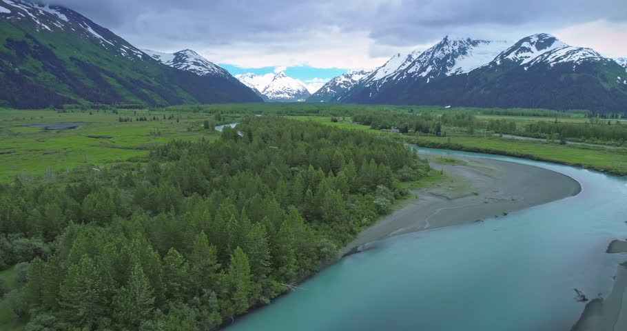 Aerial: flying over glacier river, mountain & trees near, Chugach Forest, Anchorage, Alaska