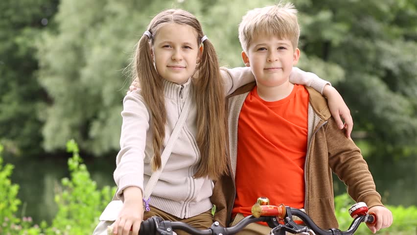 Portrait of a brother and sister. Walking on bicycles.