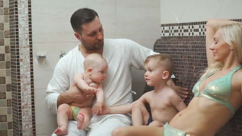 A family of four in hamam, a Turkish steam room. Young parents with two sons in the thermal zone bask in the hamam. A healthy young family with two children in a ham. Thermal center, hammam, spa