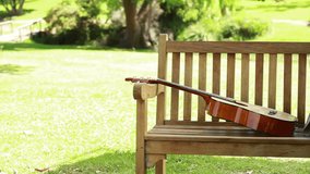Woman sitting on a bench is reading a book with a guitar beside her in a park - Powered by Shutterstock - Get 15% off with code: PIKWIZARD15