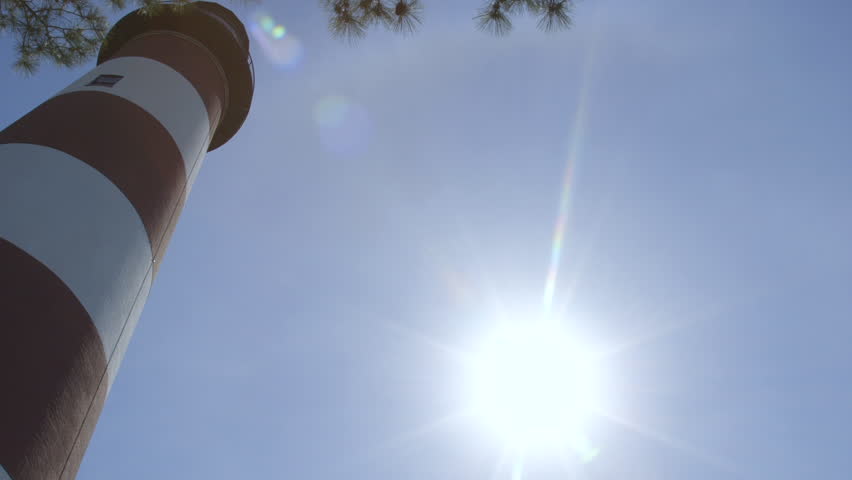 Tall Red and White Lighthouse Below Clear Blue Sky On Sunny Day