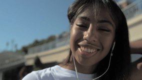 Close up of beaming girl with earphones outdoors