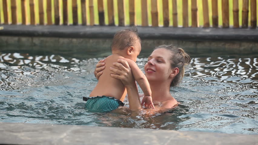 Attractive woman holding her son in the swimming pool