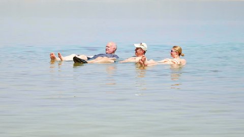 Dead Sea, Israel - May 22, 2017: People are bathing and swimming in the Dead Sea. The salinity of the dead sea water makes people floating in water. Dead sea is located between Jordan and Israel.