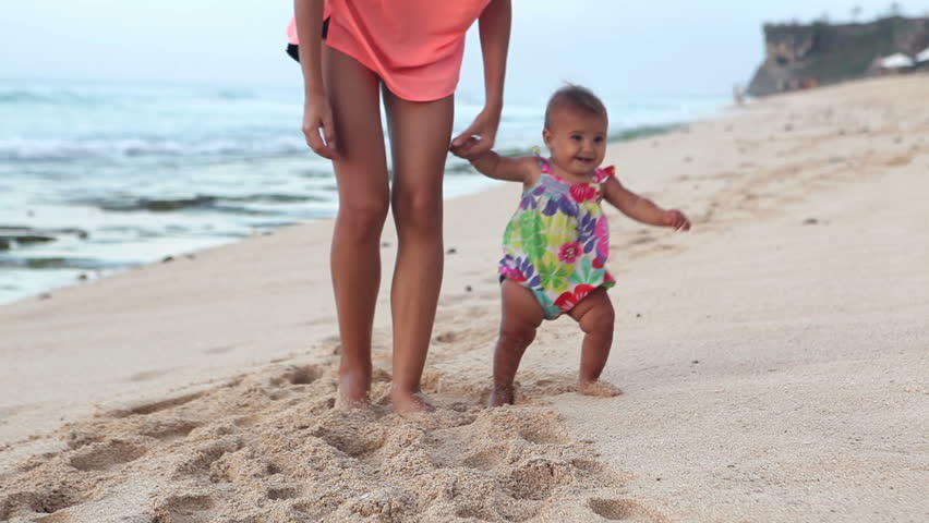 Beautiful mother with baby walking on beach