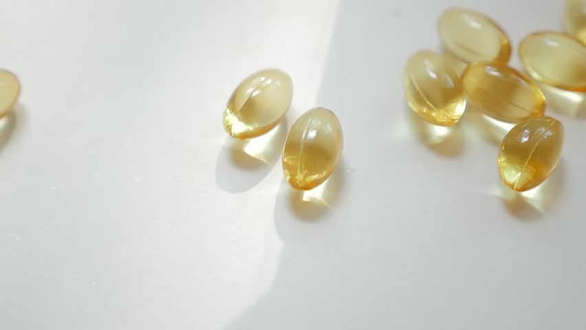 Pile of rice bran oil capsule pills supplementary product with omega 3 similar to fish oil is pouring into white isolated background. Fish oil omega 3 liquid gel capsules vitamin supplement closeup. Royalty-Free Stock Footage #29000545