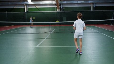 Girl and boy having tennis match practicing and training on court