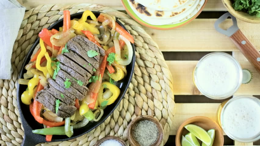 Outdoor cooking. Steak fajitas with bell peppers and yellow onion on a cast iron fajita skillet.