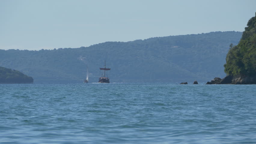 A yacht and wooden ancient touristic galley at the horizion in the Greece islands.