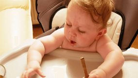 Mom feeds from spoon her little seven-month-old daughter with blond hair. In the chair for feeding. A child with a birthmark on his forehead. Slow motion 4k video
