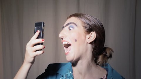 A funny ugly woman (an actor in character) making a series of selfies with a smartphone. Grotesque comedy scene.
