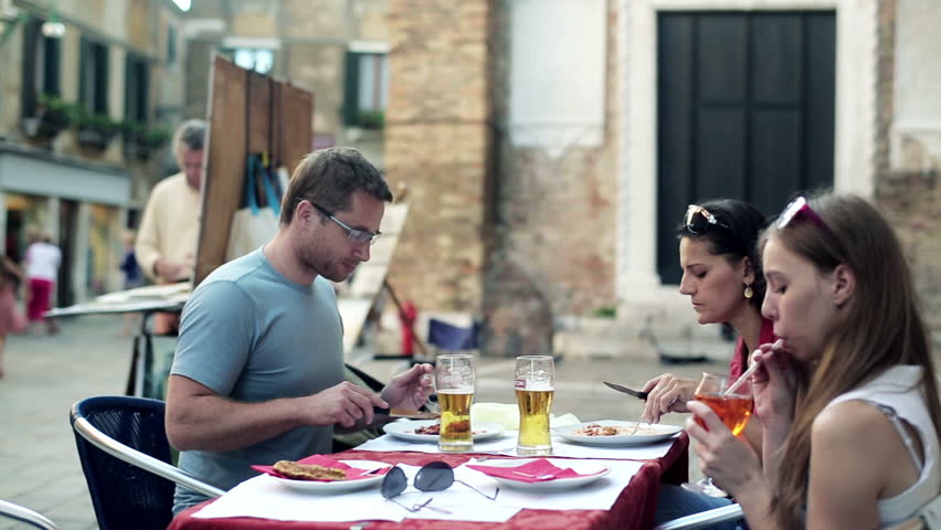 Group of friends eating and drinking beer in the restaurant, outdoors
