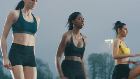 Female athletes warming up at running track before a race. In slow motion.