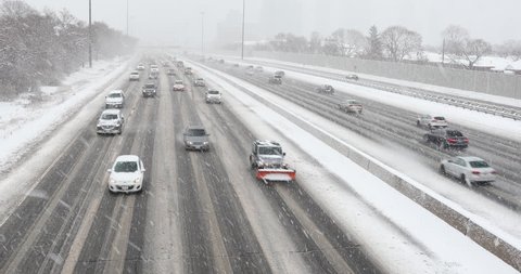 Cars driving in traffic on a snow covered road during a winter blizzard