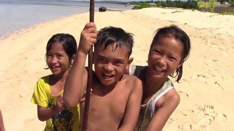 SULANGAN, PHILIPPINES - CIRCA MARCH 2017: little filipinos boys and girls play and greet happy on the sandy beach of the village of Sulangan, Eastern Samar, Philippines.