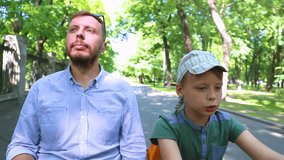 Happy family portrait having fun in summer green park. Man and little boy driving yellow pedal cart. Real time full hd video footage.