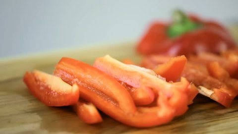 Slicing red bell pepper on a wood cutting board.