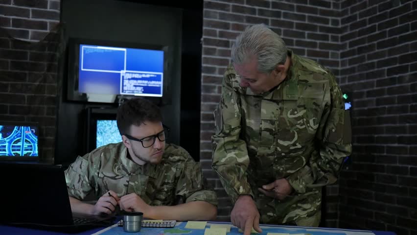 chief and soldier in camouflage uniform, at briefing, in monitoring room, view maps, discussing assault, security service and tracking terrorists, on background display screens