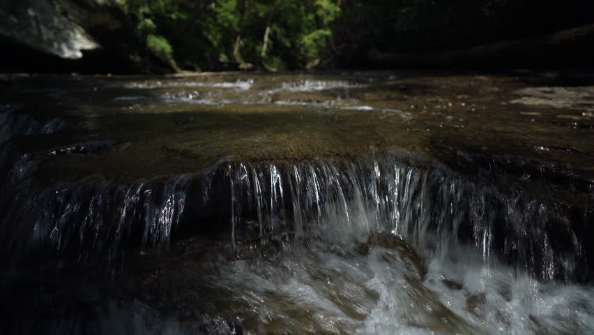 Water flowing over rocks as camera moves down stream