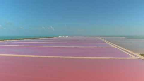 AERIAL: Flying above the stunning pink lakes of Las Coloradas, Yucatan. Spectacular colorful salt basins extending across the scenic coast of the Gulf of Mexico. Ocean surrounding beautiful salterns