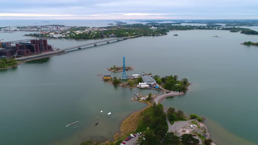 4K aerial view at Hietaniemi, Salmisaari, Lapinlahti bridge and Lauttasaari. Drone flying forward to horizon above treeline during cloudy summer day. Helsinki capital city of Finland. Scandinavia