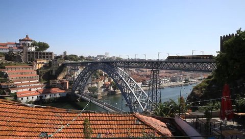 Iron bridge in Porto with view of the river and rooftops with metro passing by