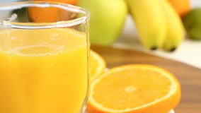Fresh citrus fruits. Rotate Video footage of the concept of a healthy food and diet. Orange juice in a glass, with a background of different fruits: banana, lime, lemon, orange. It's spinning