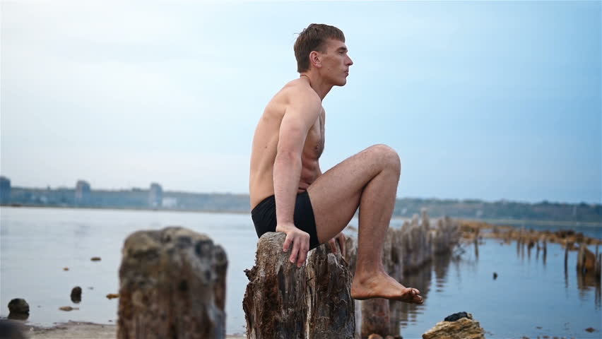 Man Yogi Makes A Stand On His Hands On Wooden Pillars. Slow Motion Effect