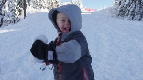 A playful young boy throws a snow ball toward the camera. 4k. Slow motion.
