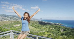 Cheerful hiker sitting with arms outstretched on railing of observation point at Diamond Head State Monument. Happy woman is enjoying wind against green landscape. Oahu, Hawaii, USA.