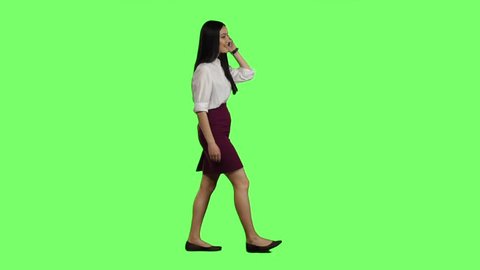 Girl of asian appearance goes to her phone rings and she starts talking. Green screen. Side view. Slow motion