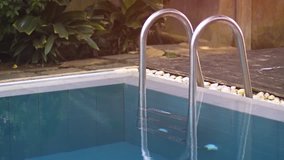 Stainless steel access ladder. mounted at the ege of a swimming pool at a tropical resort in Hikkaduwa. Sri Lanka. Video 4k UltraHD