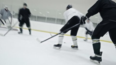 Tracking of ice hockey players from opposite teams fighting for puck during practice in rink; forward in white uniform scoring goal