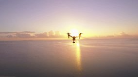 Aerial drone quad copter footage flying over ocean in cloudy sunrise morning.