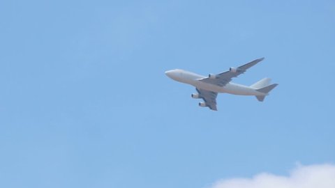 Close up of white cargo airplane passing on blue sky.