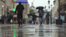 Background of rainy day on city street. Real time. People with umbrellas in the rain going to or from work. Blurred bokeh. Naturale backdrop