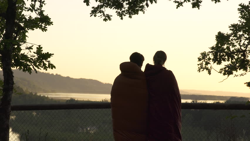 Wide Shot Of Camping Couple In Sleeping Bags Cuddling/Enjoying The Sunset In The Columbia River Gorge, Oregon