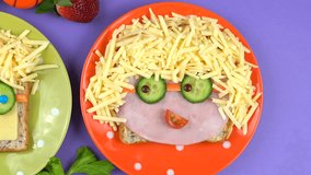Back to school fun lunches concept, making childrens faces sandwiches on bright colorful background, close up pan and zoom out.