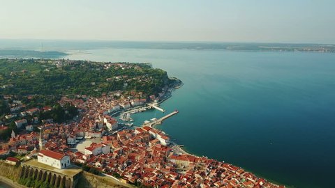 4K. Flight over old city Piran in the morning, aerial panoramic view with old houses, Tartini Square, St. George's Parish Church, fortress and marina.