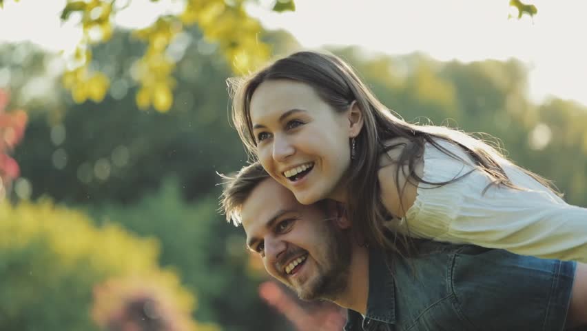 Happy Couple Having Fun Outdoors. SLOW MOTION 4K. Smiling man and woman in love doing piggyback. Joyful young family.