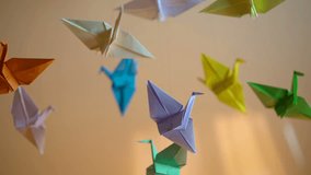Origami cranes slowly swinging in air, creative hobby, colorful background - Powered by Shutterstock - Get 15% off with code: PIKWIZARD15