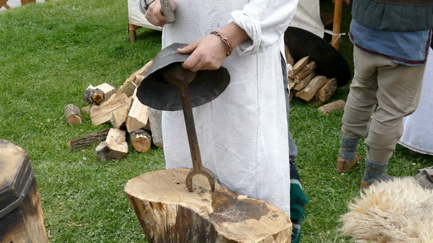 Dacian worker woman makes a demonstration of making a ancient helmet of battle from metal, in a classic way. APULUM ROMAN FESTIVAL organized by the City Hall. 4K footage.