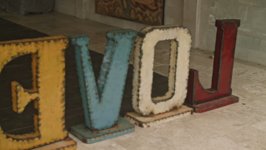 Man and woman having fun, running around and moving large letters in the garden
