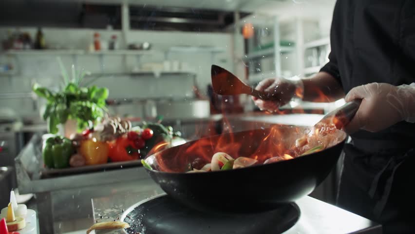 close-up of a chef working the wok with flames roasting mixed colorful vegetables tossing them , restaurant kitchen , slow motion Royalty-Free Stock Footage #29136106