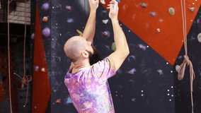 Professional climber plans his next route on climbing wall. Video 1080p resolution