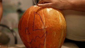 Son watches mother carve jack-o-lantern