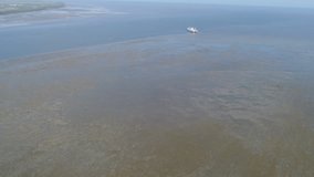 Aerial drone ; footage of ocean Zoom in, see a floating boat in the sea.